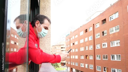 virus man with covid-19 macarilla leaning out of the window using smartphone