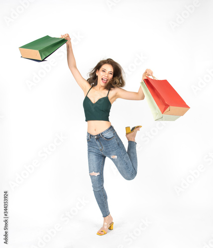 Full length attractive beauty young shopaholic asian woman in green sexy shirt and jean hand hold shopping bag jump with smile ,sale excited, spring summer fashion trend isolated on white background.