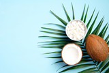 Flat lay composition with coconut and tropical palm leaf on blue background. Concept of healthy eating or organic SPA cosmetic ingredients. Summer background.