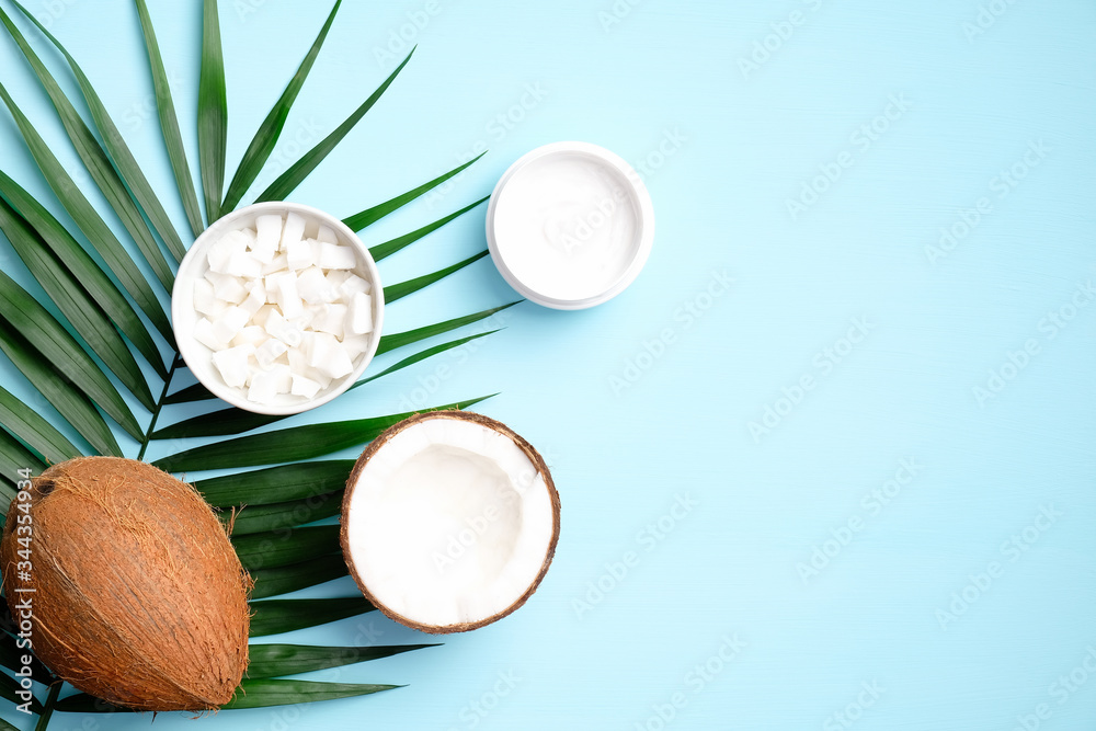Coconut cosmetic cream with palm leaf and sliced coconut on blue background. Flat lay, top view. SPA natural organic beauty product for hand skin care, body treatment Coconut cosmetic cream with palm leaf and sliced coconut on blue background. Flat lay, top view. SPA natural organic beauty product for hand skin care, body treatment