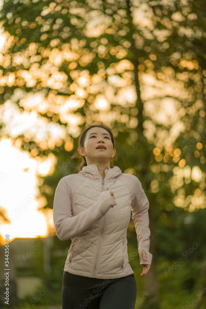 outdoors running workout - young happy and dedicated Asian Korean woman jogging at beautiful city park or countryside trail on sunset enjoying fitness and cardio activity outdoors running workout - young happy and dedicated Asian Korean woman jogging at beautiful city park or countryside trail on sunset enjoying fitness and cardio activity