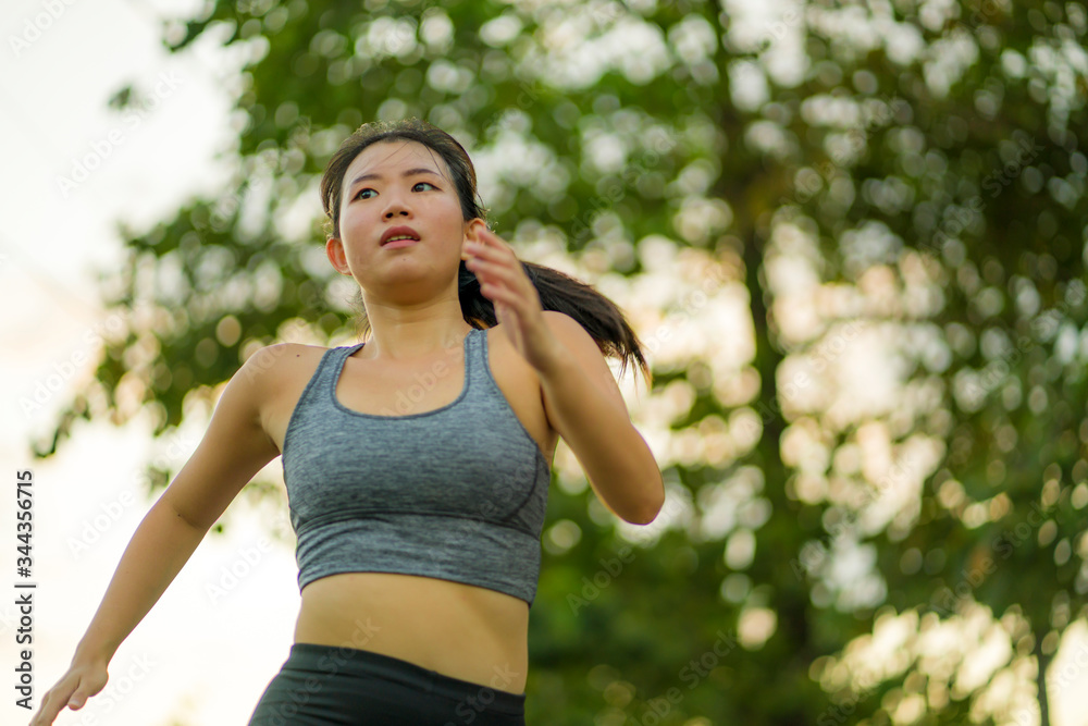 outdoors running workout - young happy and dedicated Asian Korean woman jogging at beautiful city park or countryside trail on sunset enjoying fitness and cardio activity outdoors running workout - young happy and dedicated Asian Korean woman jogging at beautiful city park or countryside trail on sunset enjoying fitness and cardio activity