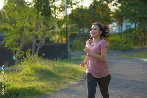 outdoors running workout - young happy and dedicated Asian korean woman jogging at beautiful city park or countryside trail on sunset enjoying fitness in healthy lifestyle