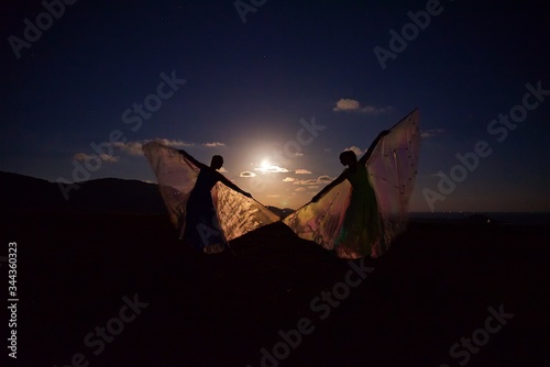 women in dresses dancing in the moonlight, night ballet under the stars of space, a couple with beautiful wings fly like butterflies, a wonderful place for night dances on Samui