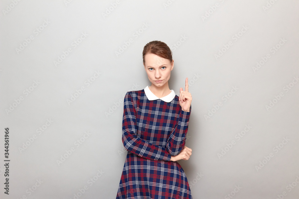 Portrait of serious focused young woman pointing up with index finger Portrait of serious focused young woman pointing up with index finger