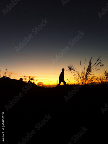 silhouette of a man walking to greet the sunrise.