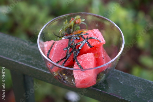 Raw tuna sashimi poke in a glass bowl with nori seaweed strips on top