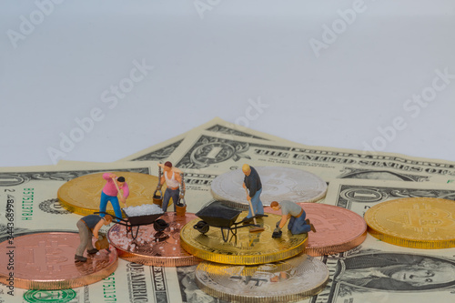 miniture people with crypto currency gold silver bronzen bitcoin with dollar banknotes photo