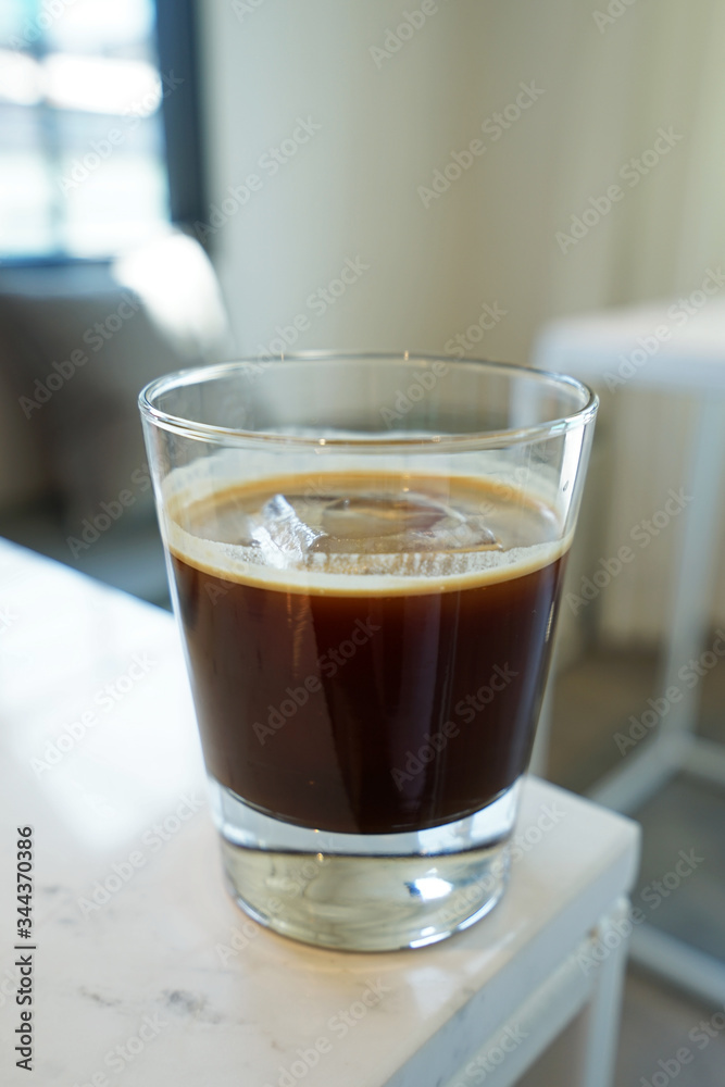 Close up glass of iced black Americano coffee on white table Close up glass of iced black Americano coffee on white table