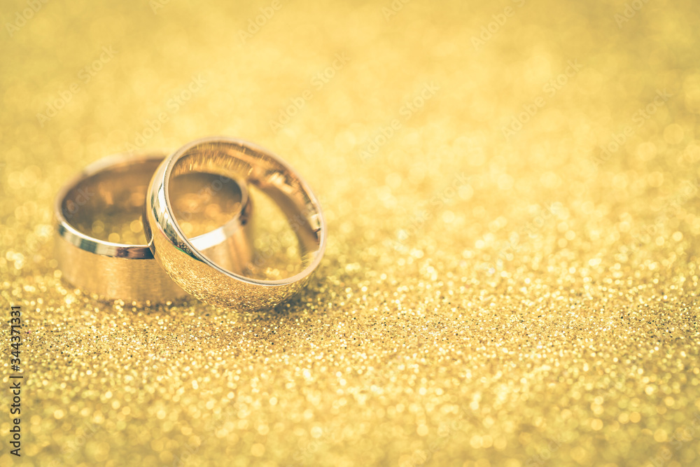 Gold wedding rings of bride and groom on gold gliter Gold wedding rings of bride and groom on gold gliter