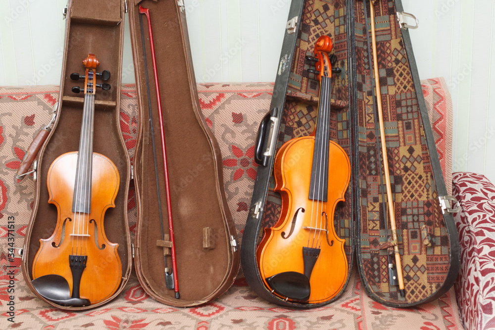 Naklejka premium Two yellow-orange violins of a different sizes with bows and cases 