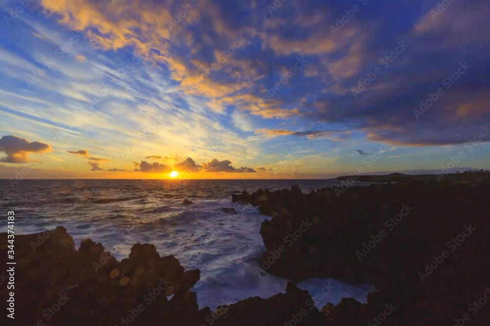 Sun rising from behind Pacific ocean in Hawaii, Hana. Waves break in the foreground while colorful clods traverse the sky. Time lapse. Sun rising from behind Pacific ocean in Hawaii, Hana. Waves break in the foreground while colorful clods traverse the sky. Time lapse.