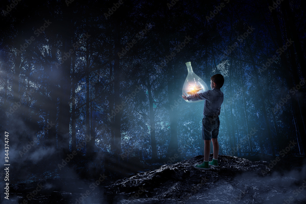 Boy holding glass flask with landscape inside it Boy holding glass flask with landscape inside it