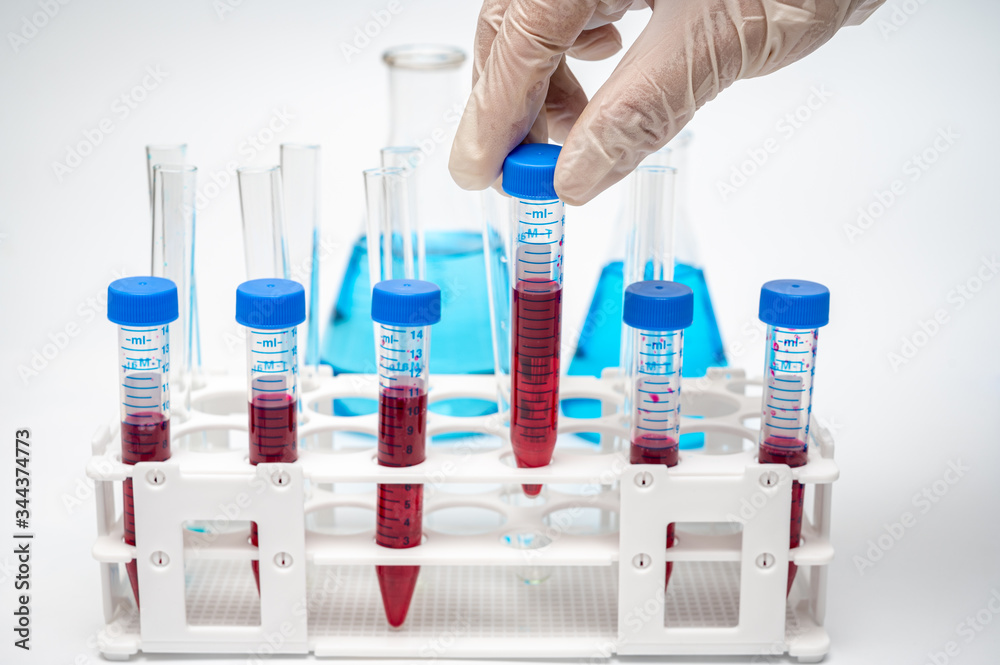 The hands of the researcher holding a centrifugal tube containing red liquid The hands of the researcher holding a centrifugal tube containing red liquid