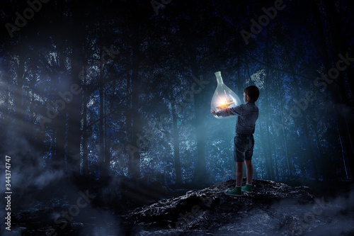 Boy holding glass flask with landscape inside it © Sergey Nivens