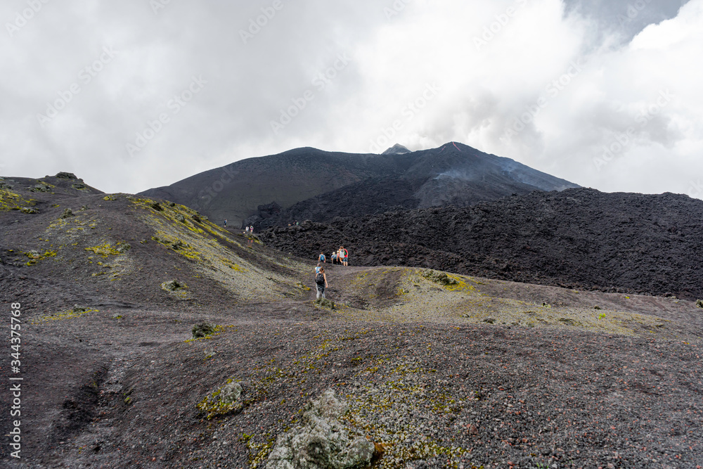 Los turistas van caminando por el camino que los lleva a las rocas volcánicas.