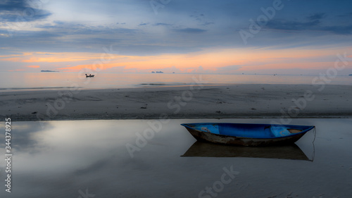 Dinghy sitting in tidal pool at beach at low tide during sunset
