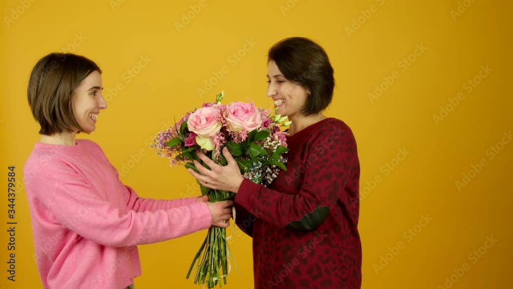 Excited girl presenting flowers and kissing mother Excited girl presenting flowers and kissing mother