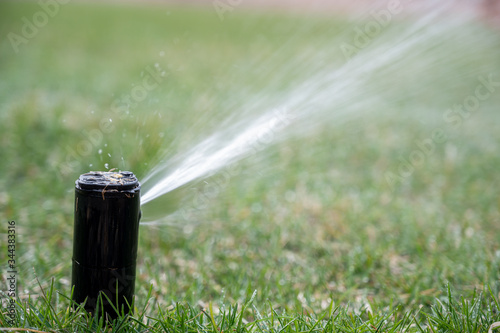 pop up automatic water sprinkler spraying jet across lawn