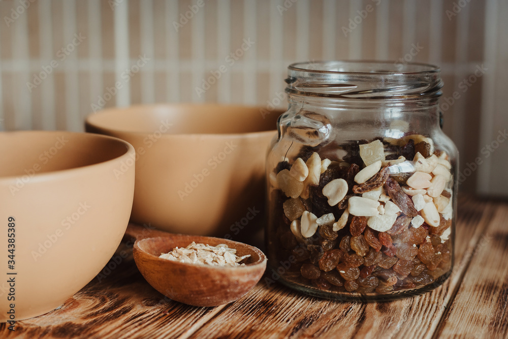 Oatmeal in a wooden spoon on a wooden background and dried fruit in a glass jar. The concept of a healthy diet and healthy lifestyle. Oatmeal in a wooden spoon on a wooden background and dried fruit in a glass jar. The concept of a healthy diet and healthy lifestyle.