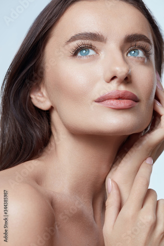 Beauty. Beautiful Woman Touching Face Close Up Portrait. Blue-Eyed Brunette Model With Perfect Skin And Natural Makeup Looking Away.
