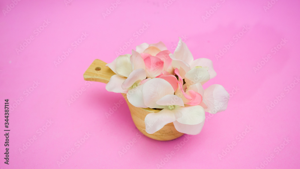Flowers in a wooden cup on pink background