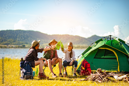 Team of asian climbers hiker are sitting and enjoying a drink after a set up outdoor tent in the forest path autumn season. Hiking, hiker, team, forest, camping , activity concept.
