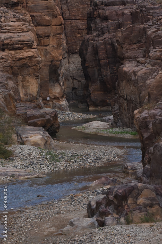 Entrance to the Wadi Mujib canyon in Jordan. Steep rocks and a rapid flowing river carved. Difficult crossing and attraction for tourists on the water route.