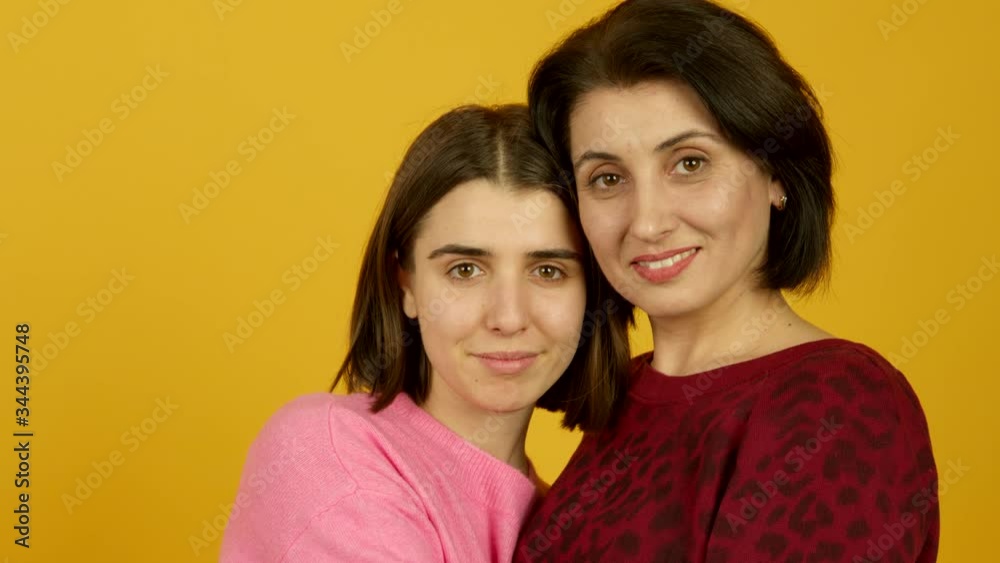 Middle aged mother and adult daughter looking at each other and embracing with smile Middle aged mother and adult daughter looking at each other and embracing with smile
