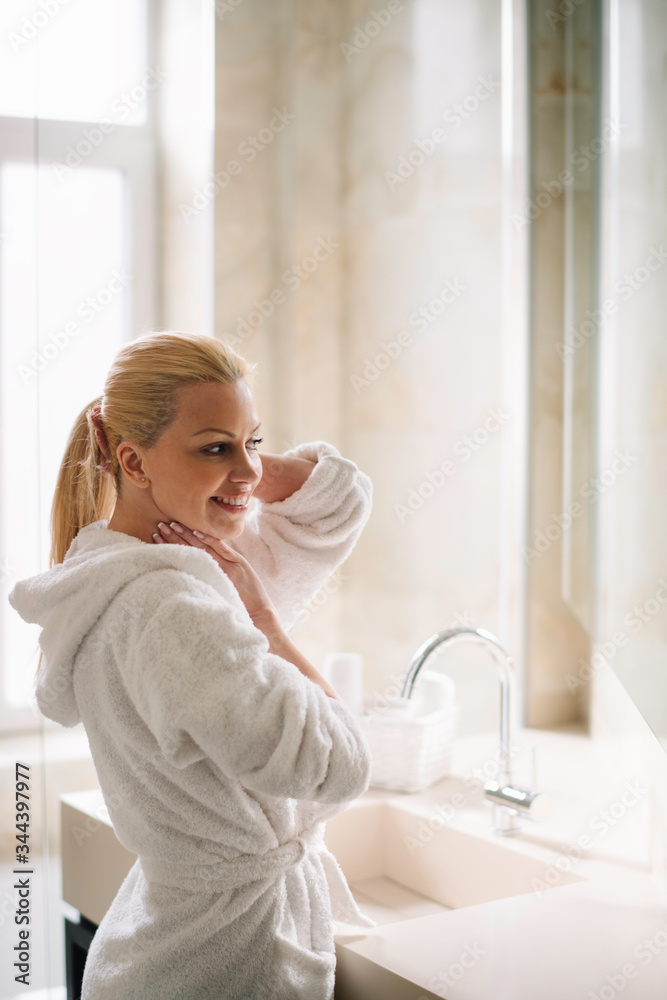 Beautiful woman enjoying in hotel. Young happy women in bathrobe use the cream for the body. Beautiful woman enjoying in hotel. Young happy women in bathrobe use the cream for the body.