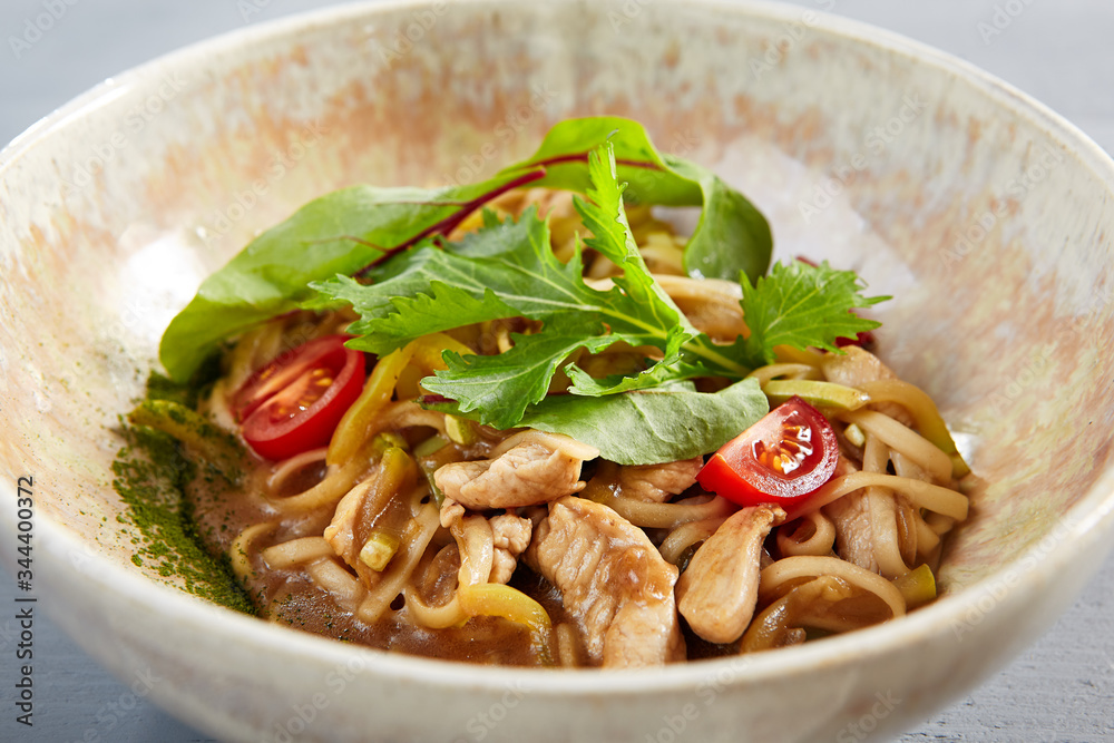Asian noodles with chicken in beige bowl