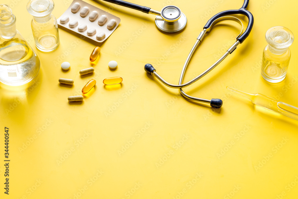 Flu treatment - pills and stethoscope on yelllow table copy space Flu treatment - pills and stethoscope on yelllow table copy space