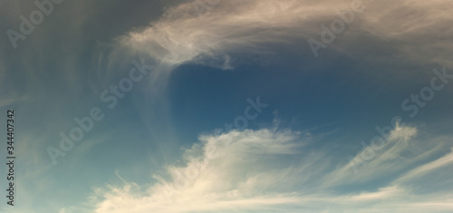 Blue sky with warm light clouds. Clouds texture. Blue background