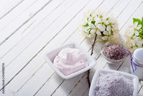 skin care product samples and cherry blossom on white wood table background