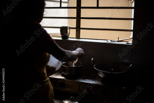 Silhouette of an Indian woman cooking in the kitchen during lock down period. Indian lifestyle in home quarantine.