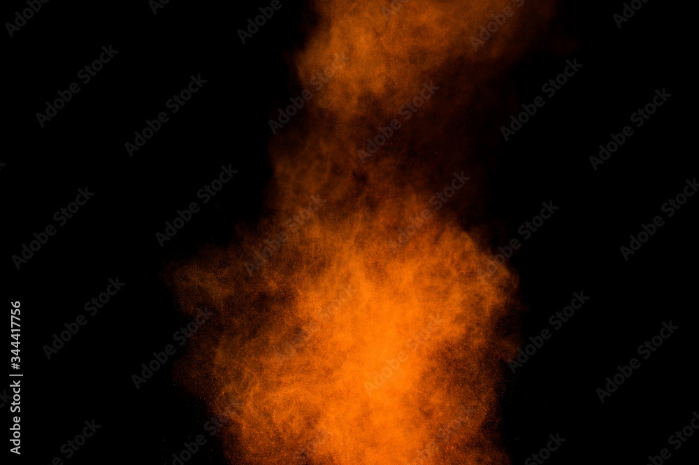 Orange powder explosion on black background. Colored powder cloud. Colorful dust explode. Paint Holi.