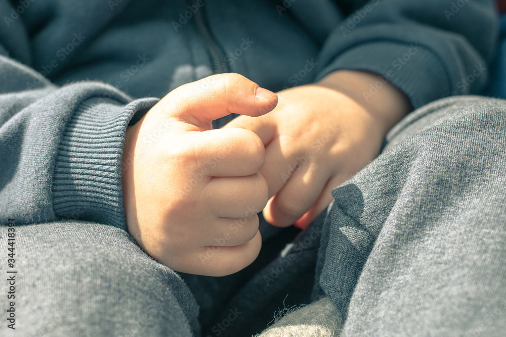 Hands of a little boy. Little boy sits with folded arms