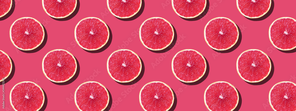 Grapefruit pattern on pink background. Top view. Creative design, minimal flat lay concept. Summer time. Tropical travel, exotic fruit. Vegan and vegetarian food