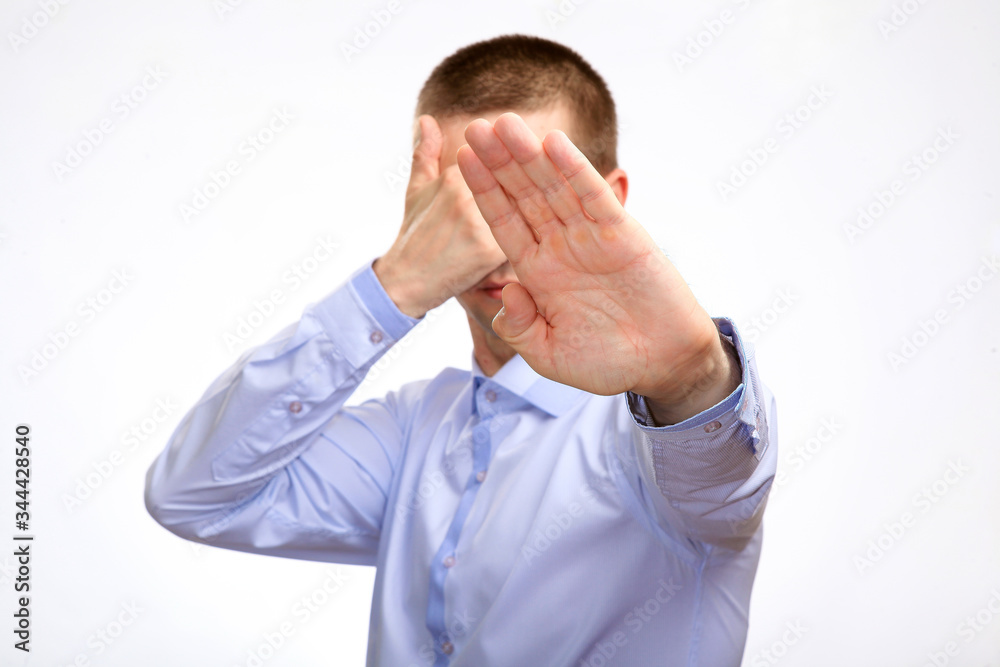 frightened cowardly man put his hands in front of him in fear of protection, in a blue light everyday shirt. Isolated frightened cowardly man put his hands in front of him in fear of protection, in a blue light everyday shirt. Isolated