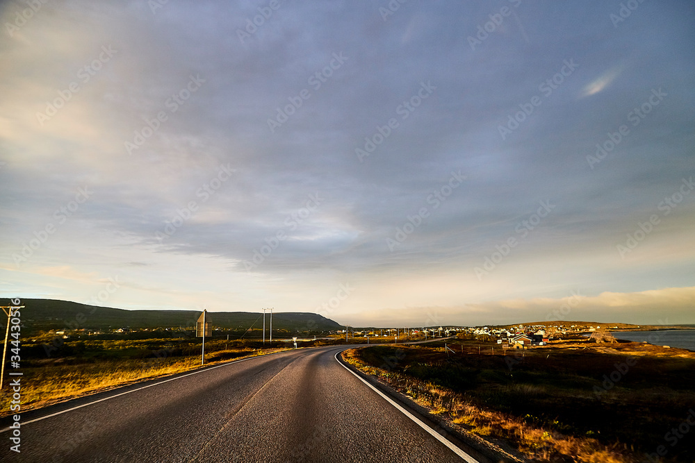 View on the road and interesting landscape with tundra, village and cloudy sky. Landscape in Norway