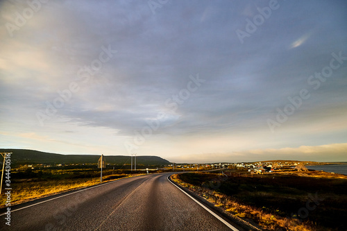 View on the road and interesting landscape with tundra, village and cloudy sky. Landscape in Norway