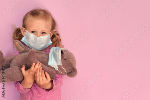 Girl with teddybear in face mask. Caucasian child wears facemask for protect during coronavirus Covid-19 epidemic. photo