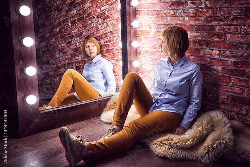 Foto Girl in shirt in front of a lighted mirror in a dark room