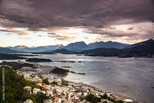 City or village in norway during sunset with sea clouds ships and sun in warm colors