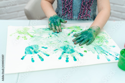 Little girl paints with fingers