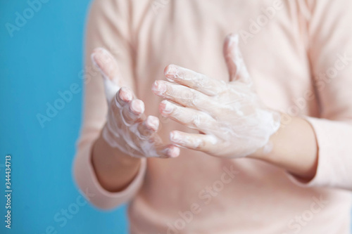 Child girl washes hands with soap on a blue background. Hand disinfection. Epidemic Covid-19.