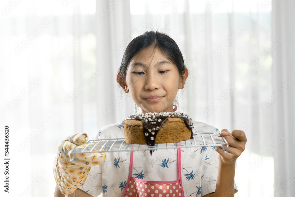Happy Asian girl showing homemade sponge cake at home, lifestyle and stay home concept.