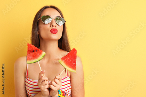 Beautiful young woman wearing sunglasses with reflection of palm trees on yellow background, space for text