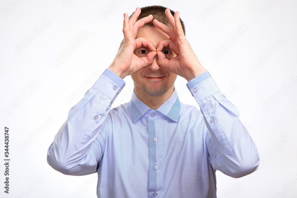 successful happy man shows the gesture OK with two hands, in a blue light casual shirt, staring at the camera. Isolated successful happy man shows the gesture OK with two hands, in a blue light casual shirt, staring at the camera. Isolated