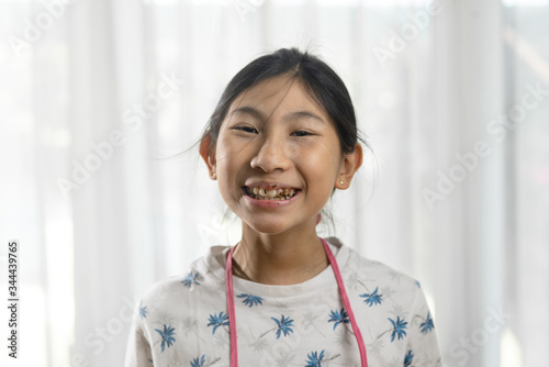 Happy Asian girl showing showing chocolate in her teeth, lifestyle and stay home concept.